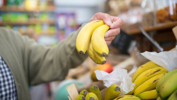 Man houdt bananen vast in de supermarkt