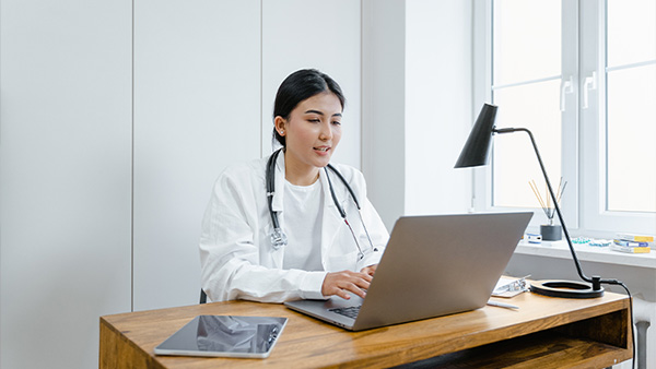 Vrouwelijke arts noteert op haar laptop