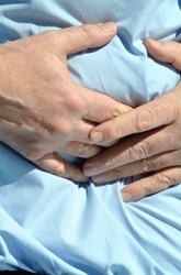 een man in een blauw hemd grijpt naar zijn maag
