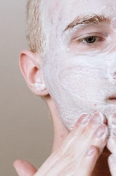 Jonge man brengt een gezichtsmasker aan.
