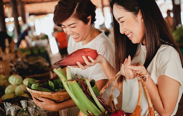 twee Aziatische vrouwen kiezen groenten op een markt