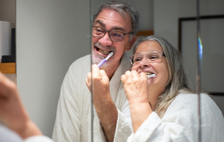 Man en vrouw poetsen samen hun tanden terwijl ze in de spiegel kijken