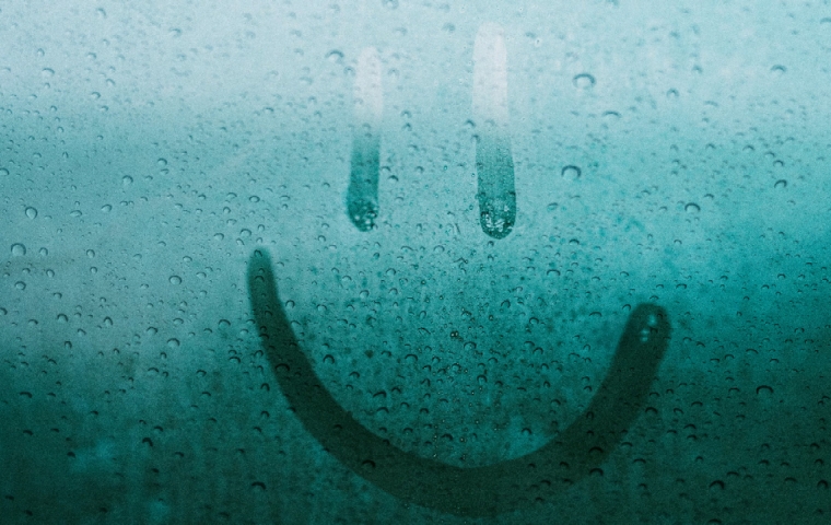 een smiley getekend op een aangeslagen raam