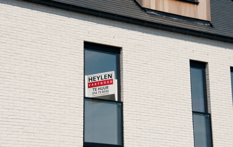Een raam met daarop een verhuurbord van Heylen Vastgoed